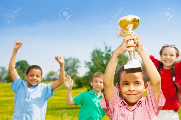 20981376-Close-shoot-of-black-happy-smiling-little-boy-holding-prize-cup-with-group-of-boys-and-girls-on-back-Stock-Photo